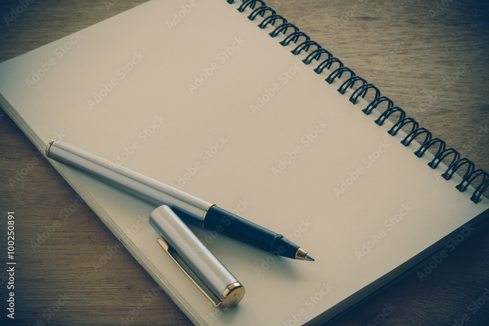 paper notebook and pen on a table with filter effect retro vinta paper notebook and pen on a table with filter effect retro vinta