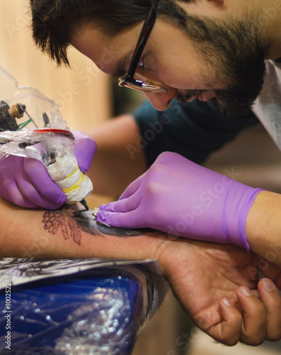 Tattoo artist does the tattoo on his arm
