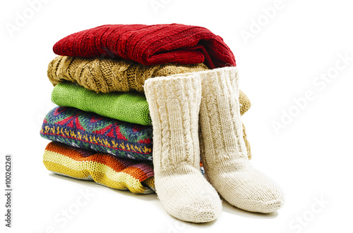 Wool socks and stack of various sweaters. Winter style. Isolated on white background 