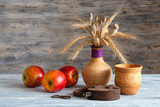 Натюрморт: старый ржавый навесной замок, глиняная посуда и красные яблоки на деревянном столе
