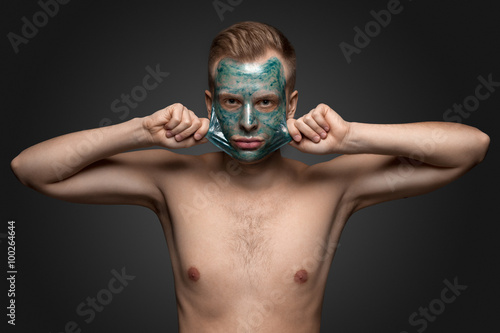 Foto Peeling off / Portrait of a beautiful young man peeling off a facial mask, face and body skin care retreat