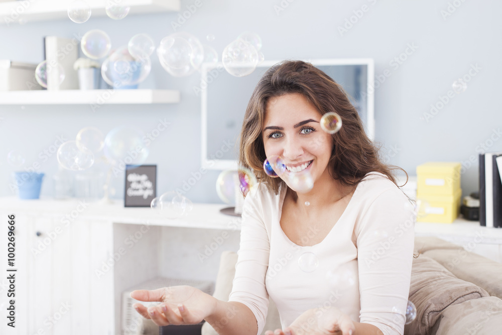 Beautiful woman blowing bubbles in her living room,having fun. Shallow depth of field Beautiful woman blowing bubbles in her living room,having fun. Shallow depth of field
