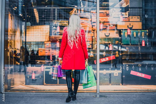 Obraz na plátně Woman looking at window shop - Young pretty girl standing in front of a boutique