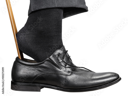 man dons black shoe with shoehorn isolated photo
