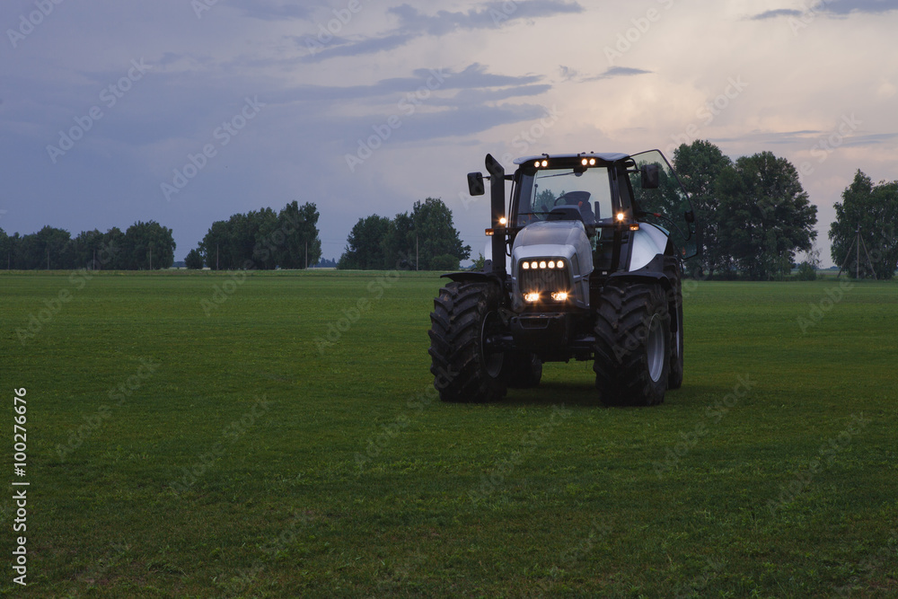 tractor with head lights in field at dusk tractor with head lights in field at dusk