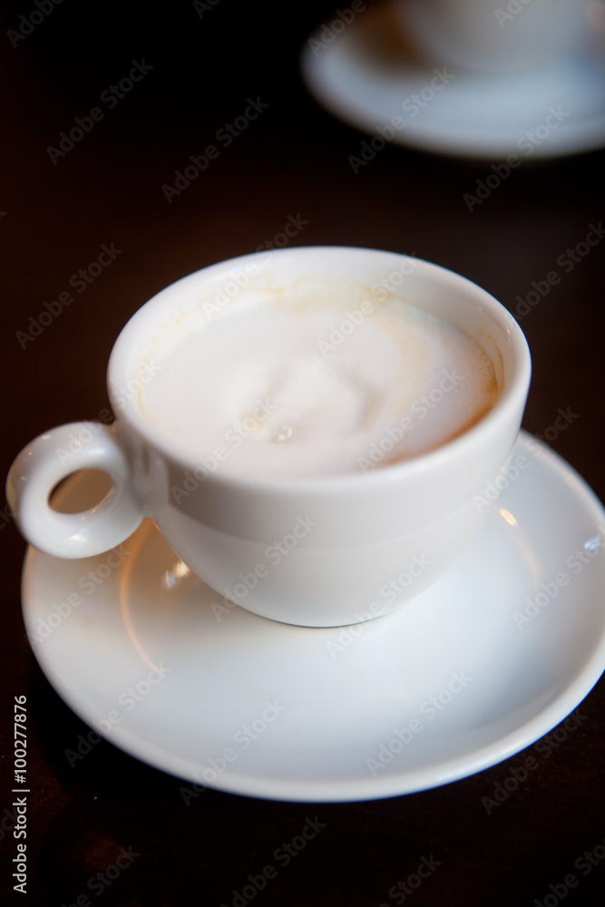 White cup of cappuccino stands on the table, selective focus 