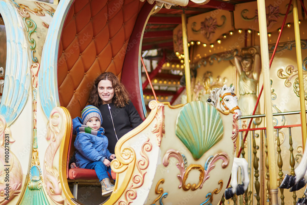 Young mother with her adorable little son on Parisian merry-go-round
