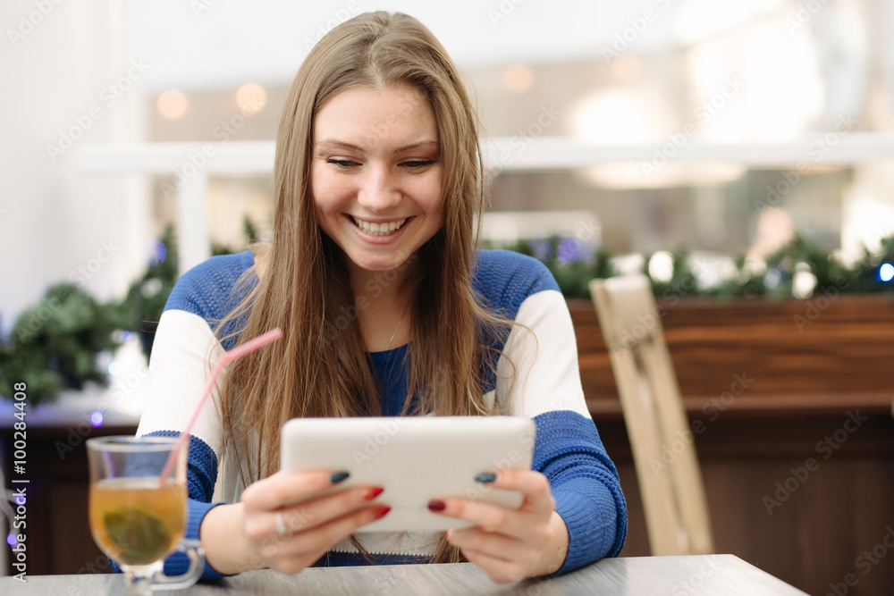 Beautiful woman using her digital tablet in light cafe and smile Beautiful woman using her digital tablet in light cafe and smile
