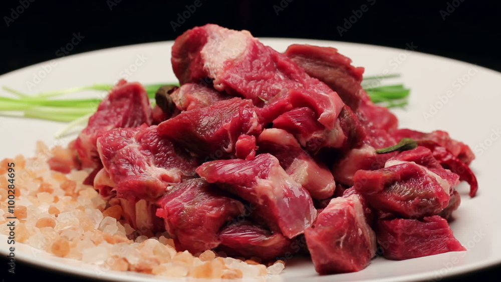 Fresh beef meat with himalayan salt and chives on a white plate, rotating Fresh beef meat with himalayan salt and chives on a white plate, rotating