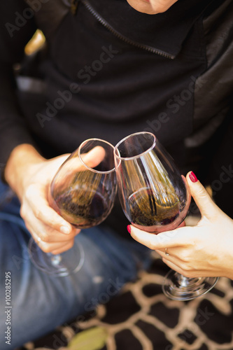 Two glasses of the red wine in hands, picnic theme