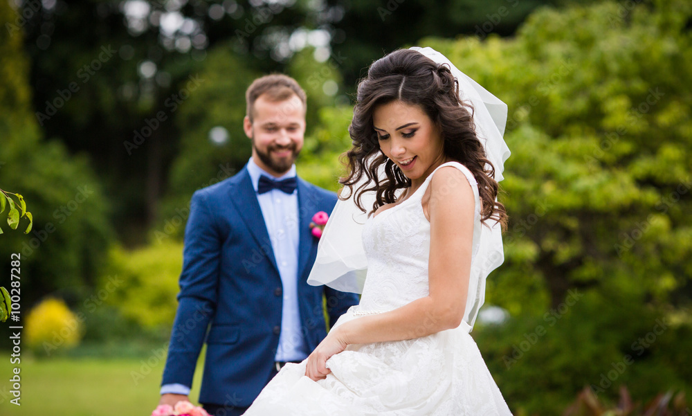 Gorgeous brunette bride in elegant dress posing in the park with Gorgeous brunette bride in elegant dress posing in the park with