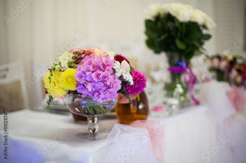 Beautiful freshly cut flowers in a glass vase on wedding recepti © IVASHstudio