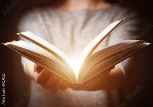 Light coming from book in woman's hands in gesture of giving