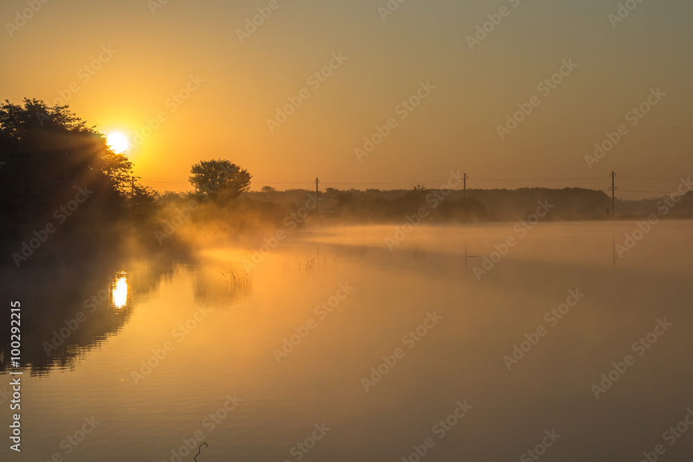 Beautiful lake in the morning mist and rising sun