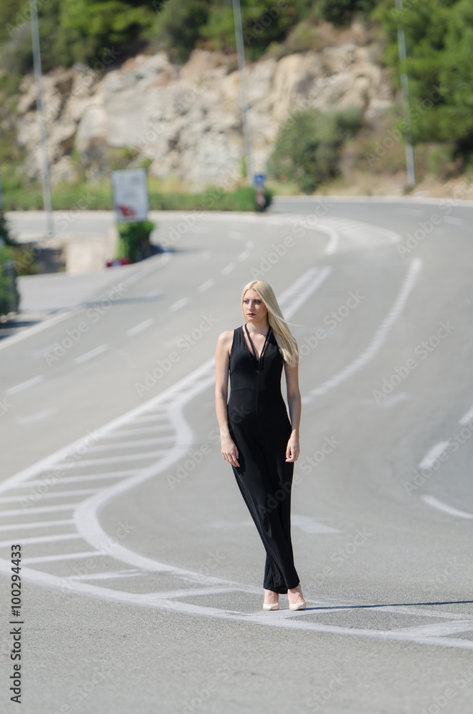Outstanding model with a slim body do a fashion shooting on the high speed road wearing a black neck jumpsuit