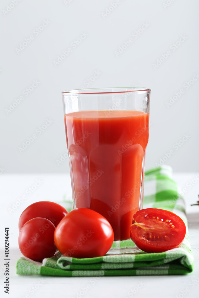 Fresh red tomatoes in basket and tomato juice in glass on white Fresh red tomatoes in basket and tomato juice in glass on white