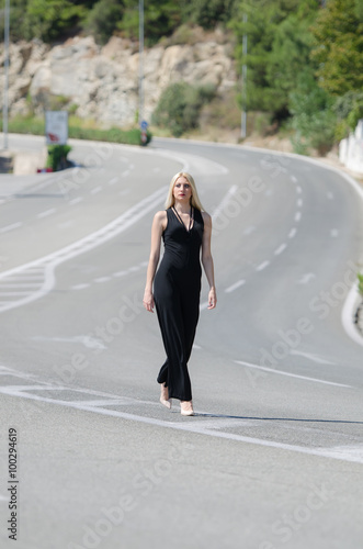 Outstanding model with a slim body do a fashion shooting on the high speed road wearing a black neck jumpsuit