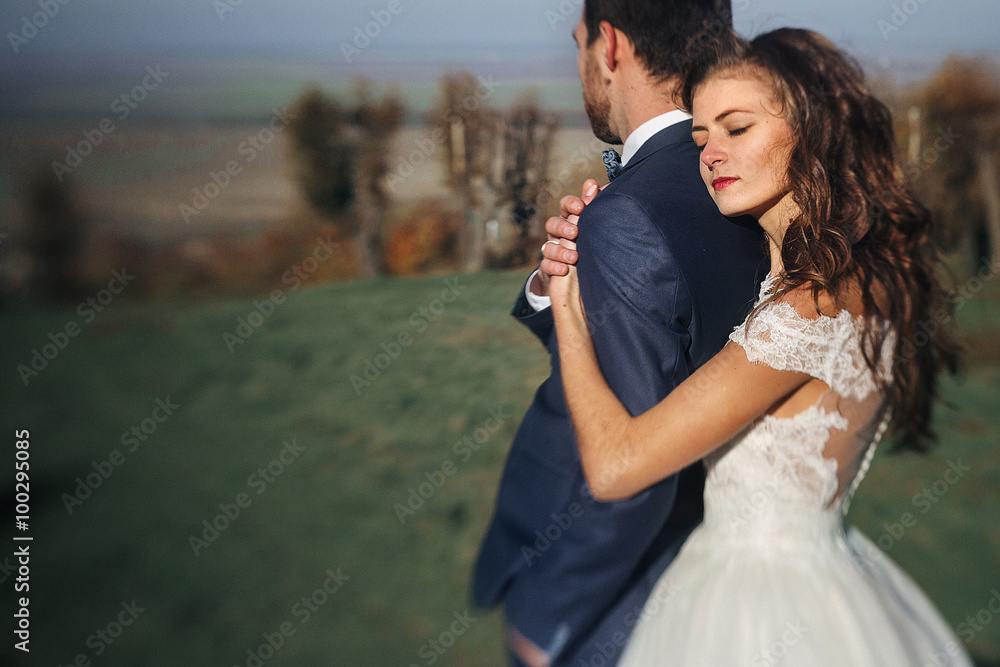 Emotional beautiful bride hugging newlywed groom from behind at Emotional beautiful bride hugging newlywed groom from behind at