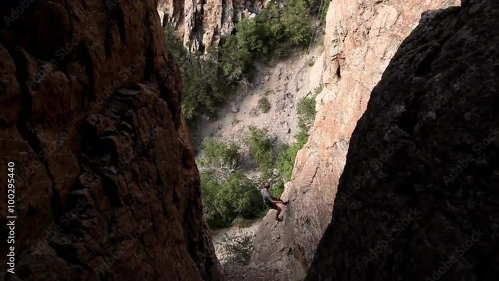 Handheld shot of a rock-climber slowly descending a craggy cliff. Handheld shot of a rock-climber slowly descending a craggy cliff.