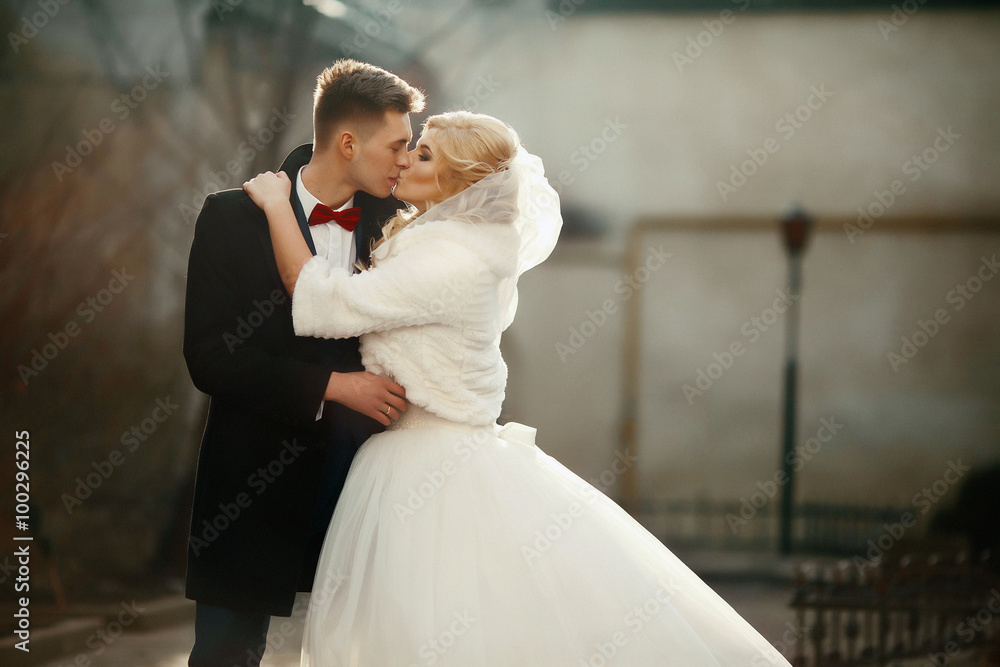 Happy newlywed groom hugging and kissing blonde beautiful bride