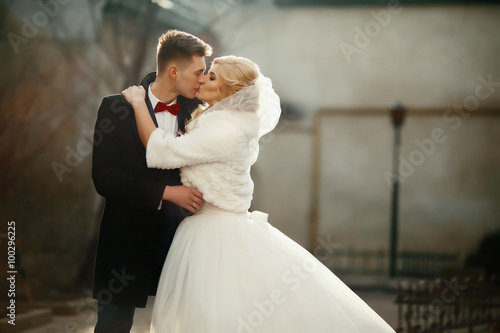 Happy newlywed groom hugging and kissing blonde beautiful bride