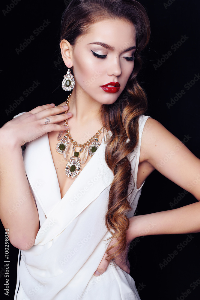  woman with long dark curly hair wears luxurious necklace and elegant dress