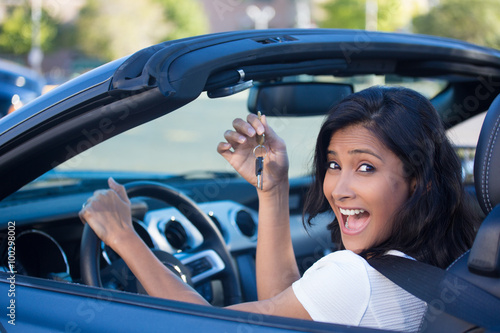 Closeup portrait, young cheerful, joyful, smiling, gorgeous woman holding up keys to her first new sports car. Customer satisfaction