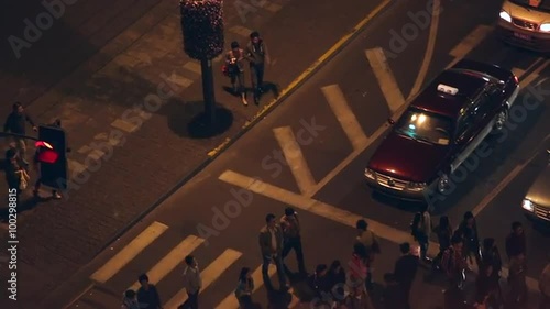 Zoomed panning view of people in crossing through traffic. photo