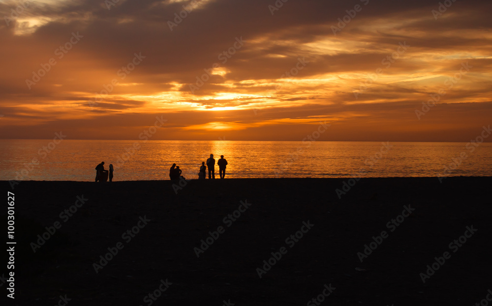 Silhouettes of people at sunset on beach