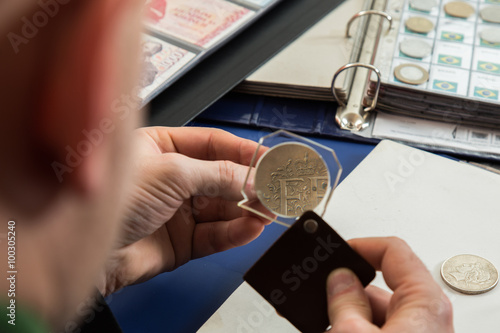 Numismatist examines  collection of coin