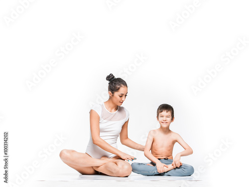 Young fit pretty mom explains her son how to do yoga exercise 