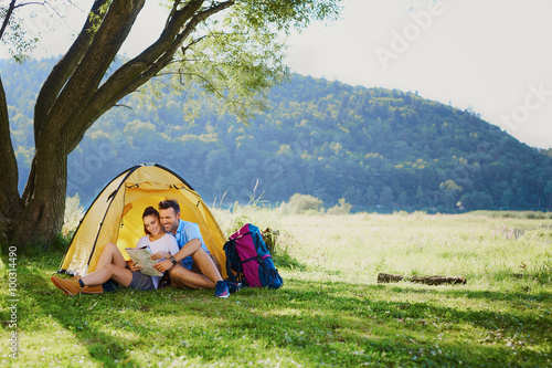 Photo of happy couple sitting in tent during hiking trip