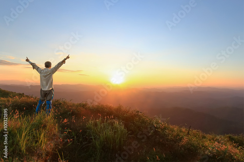 Tourist man spread hand on top of a mountain enjoying valley sun