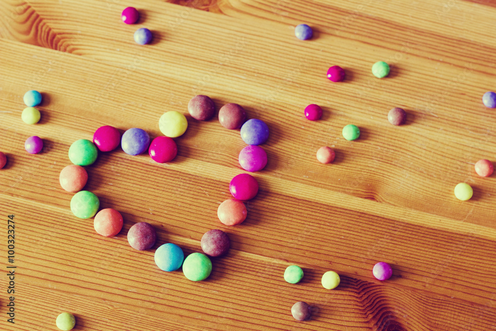 Background with color candies in the shape of a heart on the wooden table in vintage toning. Valentines day greeting card. Background with color candies in the shape of a heart on the wooden table in vintage toning. Valentines day greeting card.