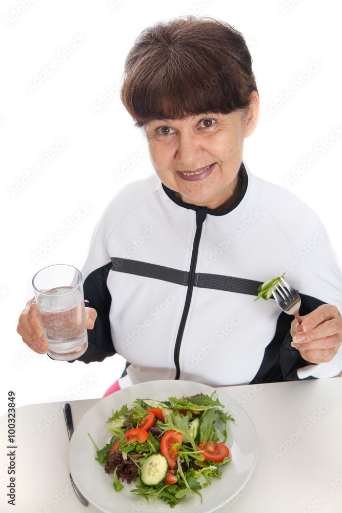 Elderly woman in sport costume eating green salad. Healthy life style concept Elderly woman in sport costume eating green salad. Healthy life style concept