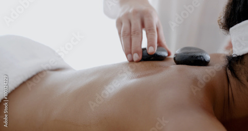 African-american woman receiving a massage with hot stone in a spa center