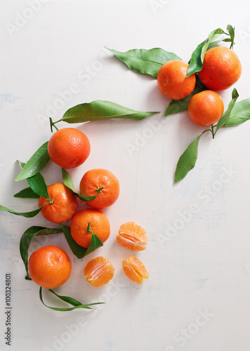 Sweet tangerines with leaves on table