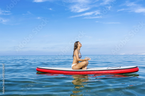 Woman relaxing over a paddle surfboard © ikostudio