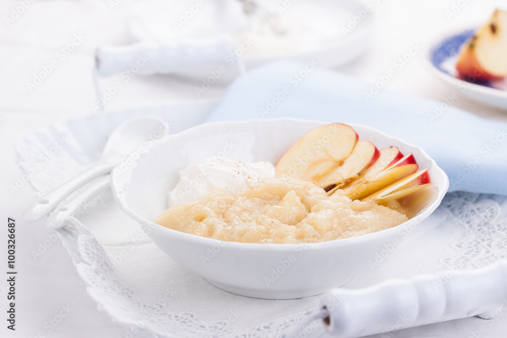 Apple puree dessert with cream and fresh apples in a white bowl on a white tea-tray. selective focus.. Apple puree dessert with cream and fresh apples in a white bowl on a white tea-tray. selective focus..