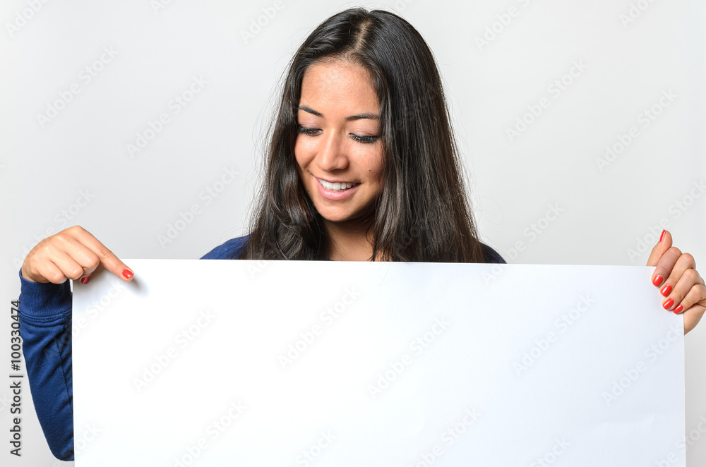 Smiling woman pointing to a blank white sign Smiling woman pointing to a blank white sign
