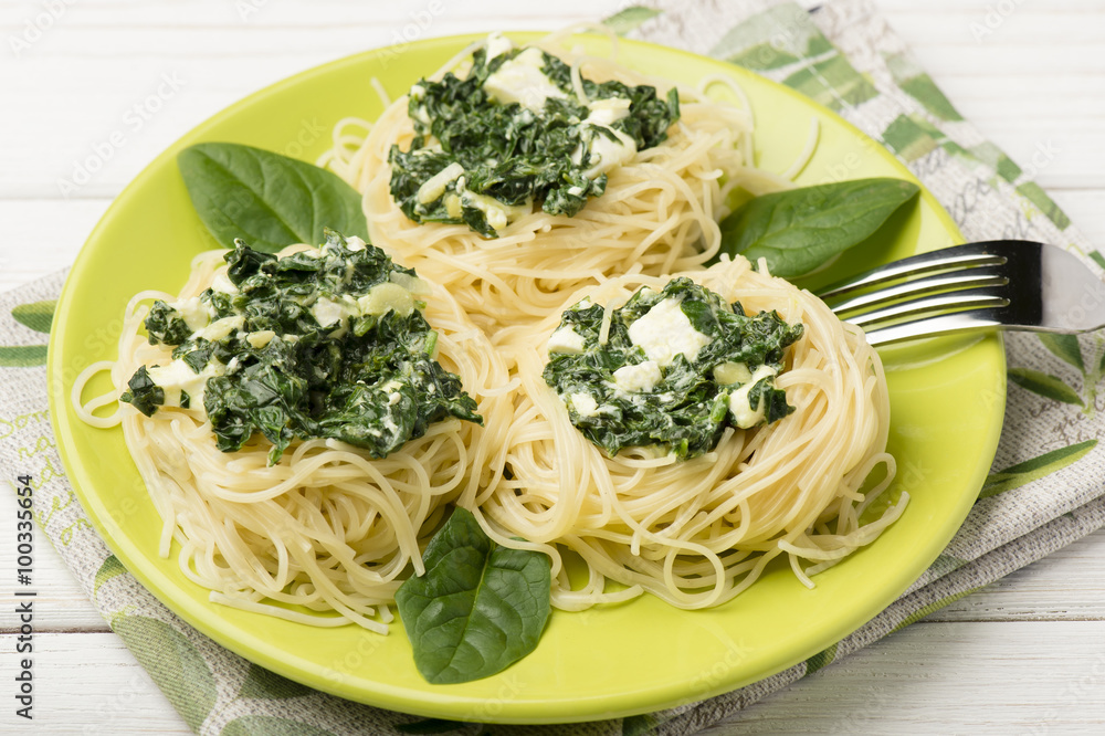 Italian pasta with spinach and feta on green plate on the wooden background. Italian pasta with spinach and feta on green plate on the wooden background.