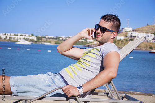 Portrait of handsome  young man talking on the phone on a sea background.Summer vacation © boryanam
