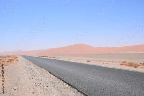 Straße in der Wüste mit Dünen im Hintergrund