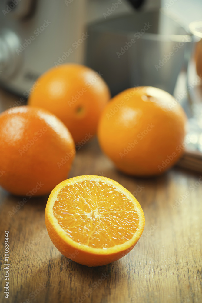 Close up shot of half sliced fresh orange on wooden kitchen table in front of juicer machine. Close up shot of half sliced fresh orange on wooden kitchen table in front of juicer machine.