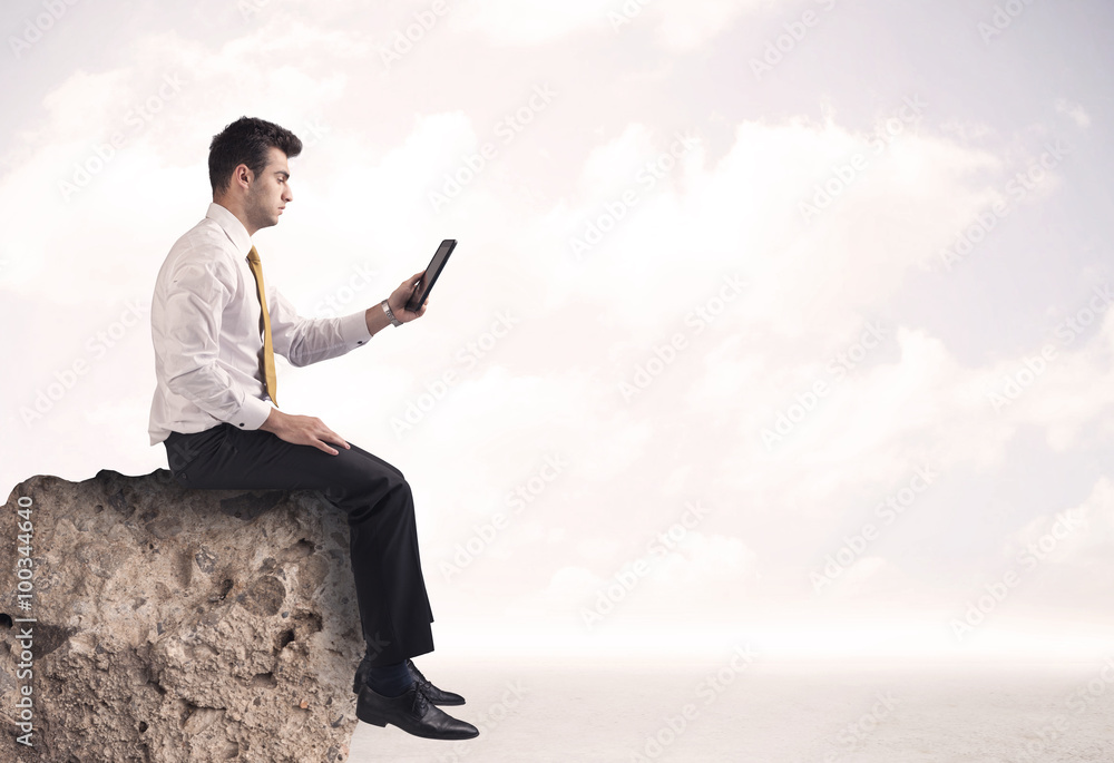 Business man sitting on stone edge Business man sitting on stone edge