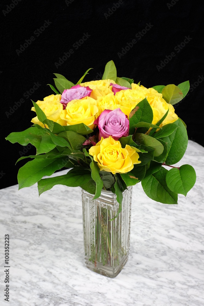 Bouquet of yellow roses with three purple in the glass vase Bouquet of yellow roses with three purple in the glass vase