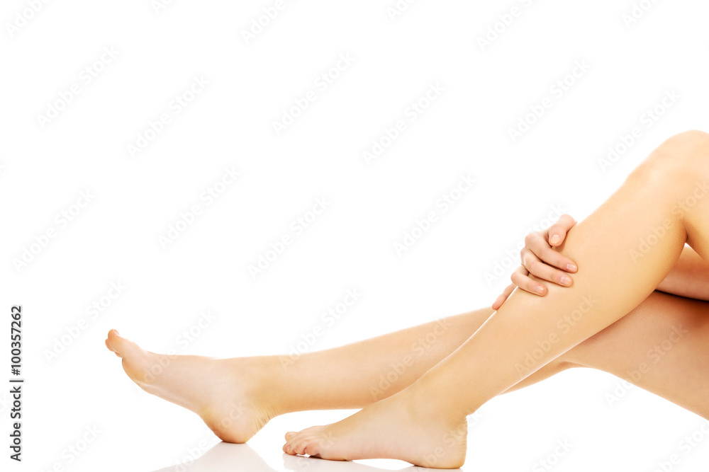 Young woman sitting on the floor and touching her legs Young woman sitting on the floor and touching her legs