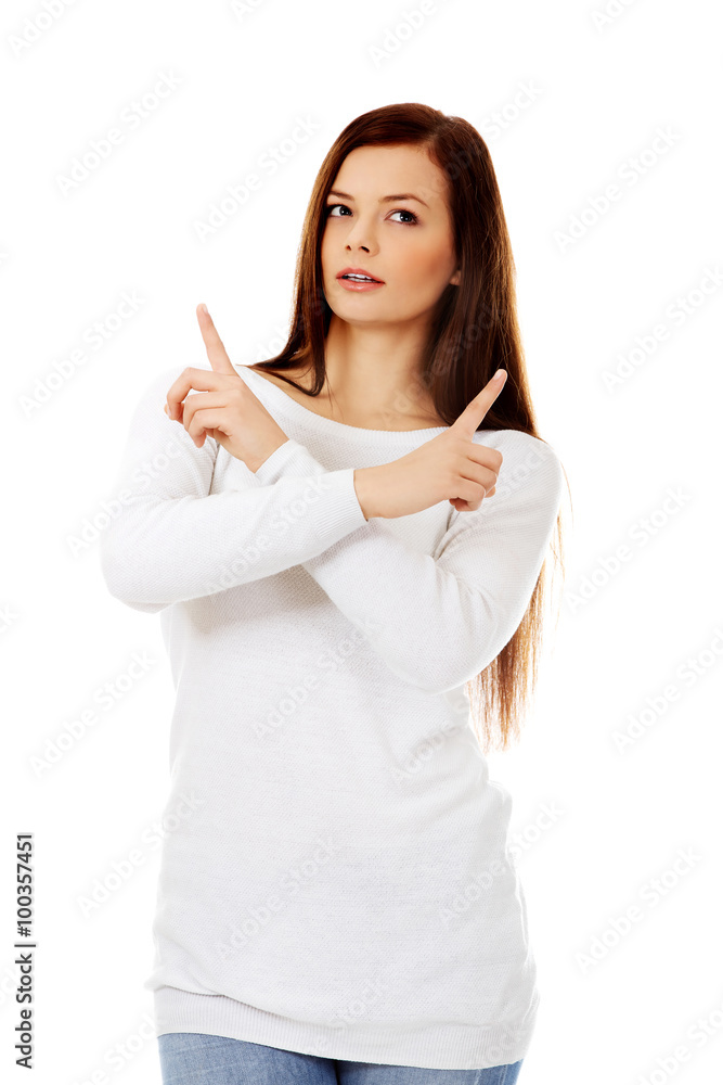 Confused young woman pointing in two different directions Confused young woman pointing in two different directions