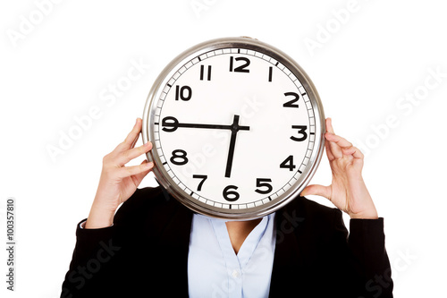 Business woman covering face with a clock