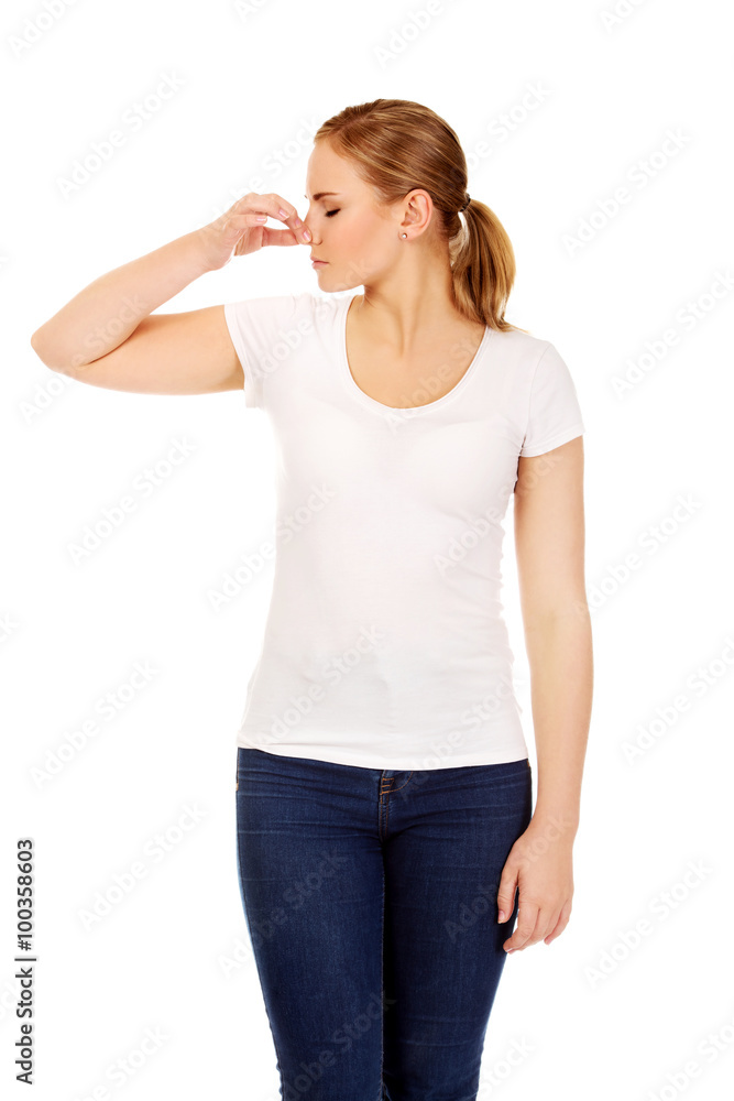 Young woman holding her nose because of a bad smell Young woman holding her nose because of a bad smell